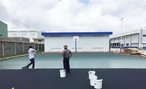 Applying paint to the surface of the basketball court